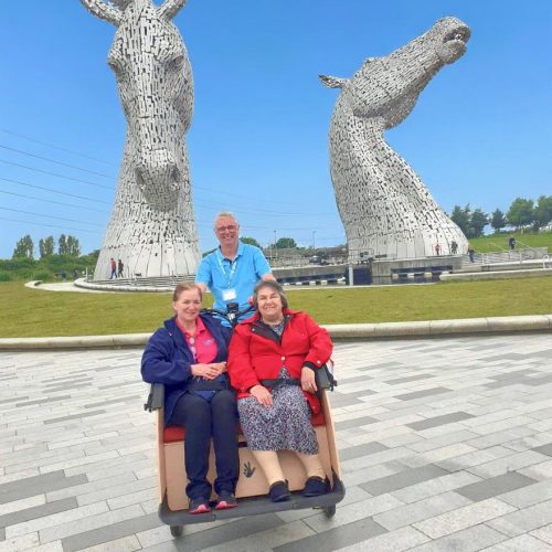 A joyful moment captured at The Kelpies in Falkirk as a Creative Homecare carer shares a sunny day out with a customer.
